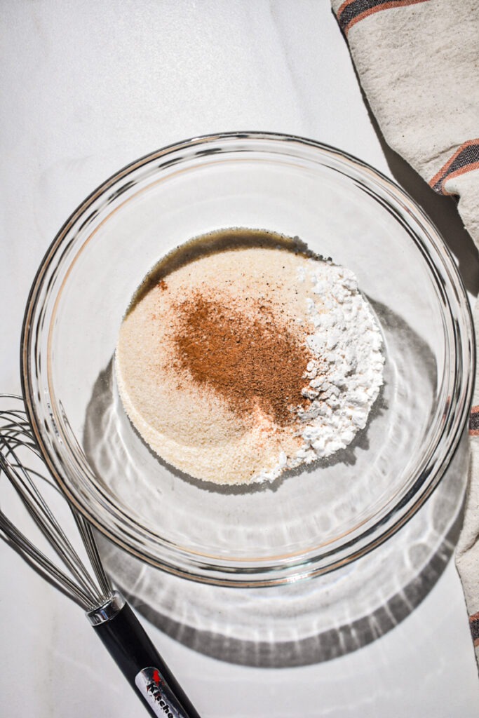 Flour, sugar, cinnamon and nutmeg in a mixing bowl.