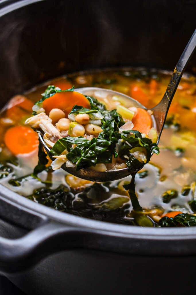 Ladle scooping up a portion of chicken white bean kale soup.