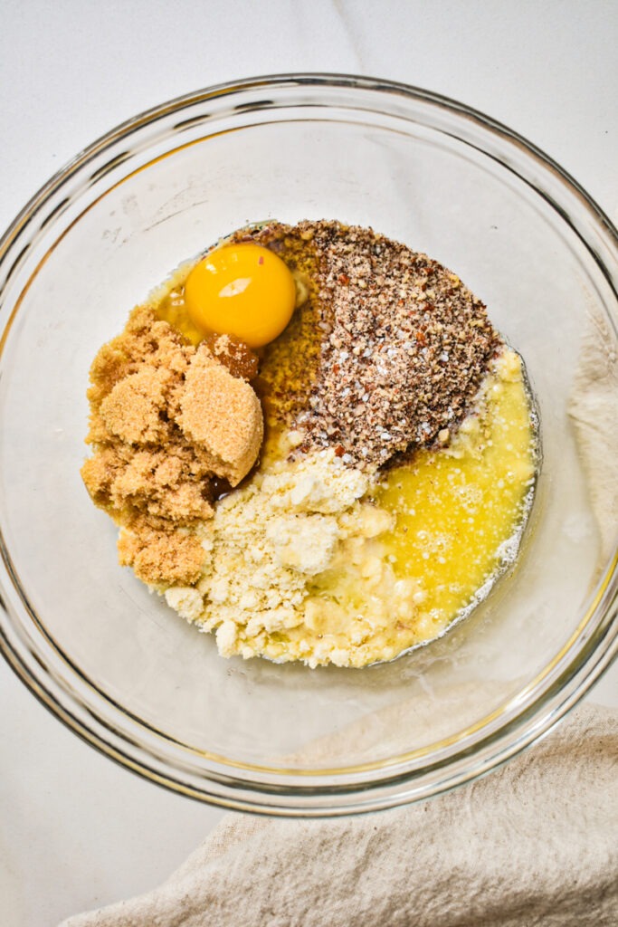 Crust ingredients including egg, brown sugar, almond flour, and melted butter in a glass bowl.