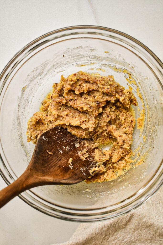 Almond pecan crust mixture stirred together with a wooden spoon