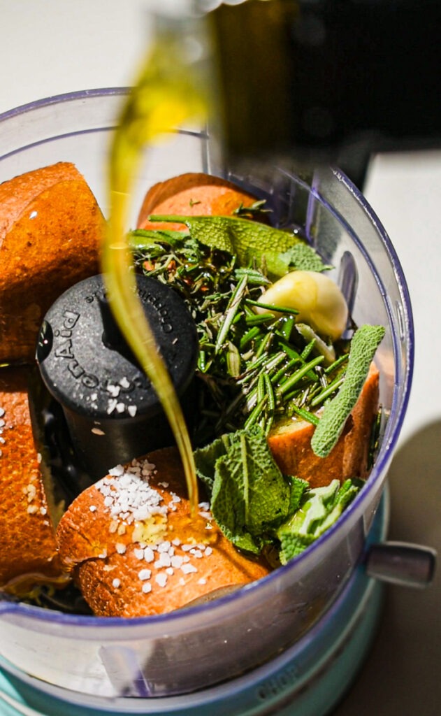 Making the breadcrumb mixture with stale bread, herbs and olive oil in a food processor.