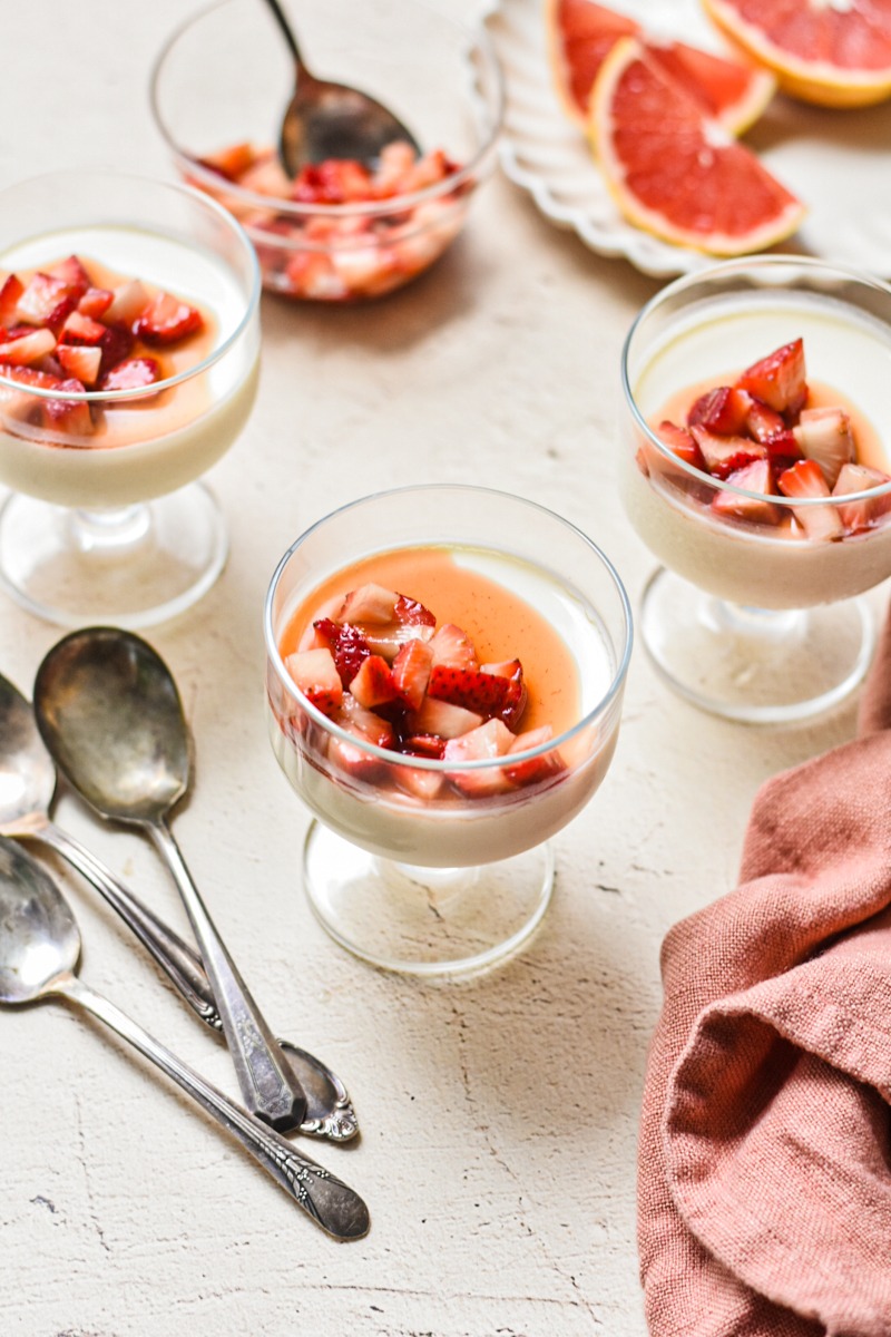 Grapefruit possets in serving glasses all topped with macerated strawberries.