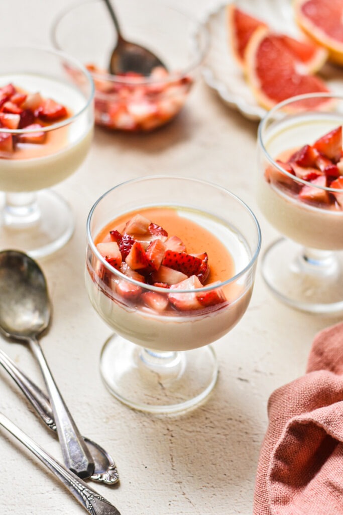 Grapefruit possets served in glasses all topped with diced strawberries.