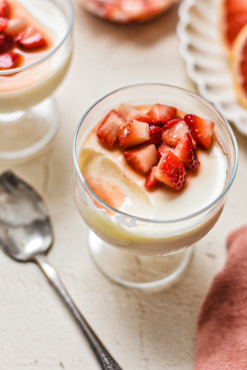 Grapefruit posset topped with strawberries with a bite missing.