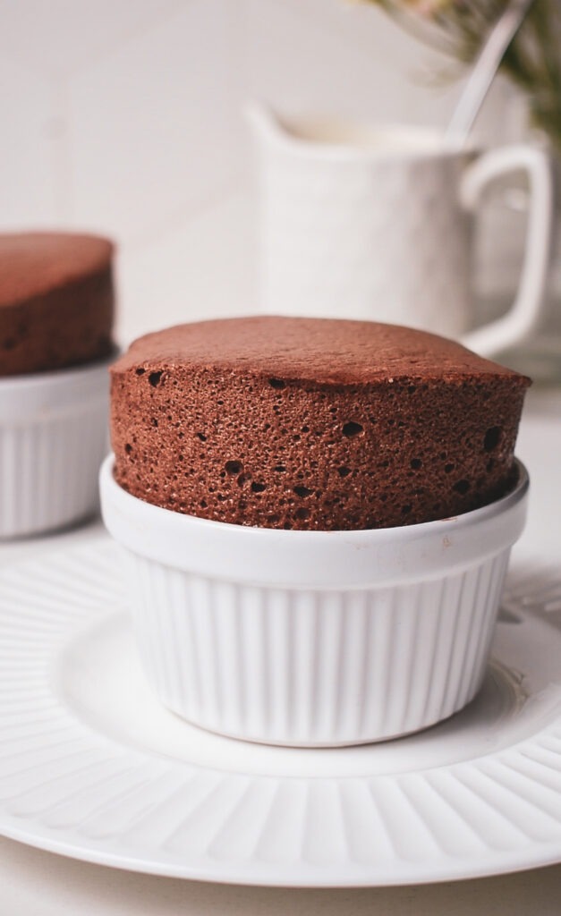 Finished chocolate soufflé in a ramekin before being dusted with powdered sugar.