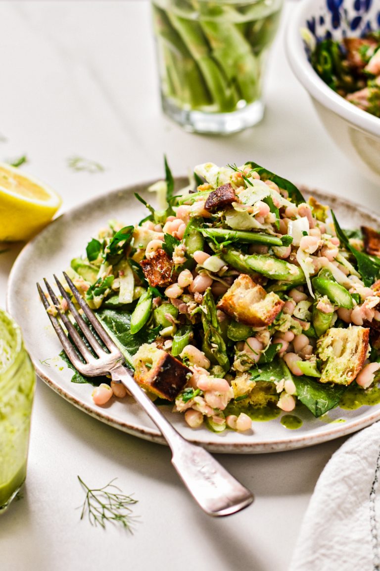 Asparagus white bean tuna salad piled on a plate with a fork.