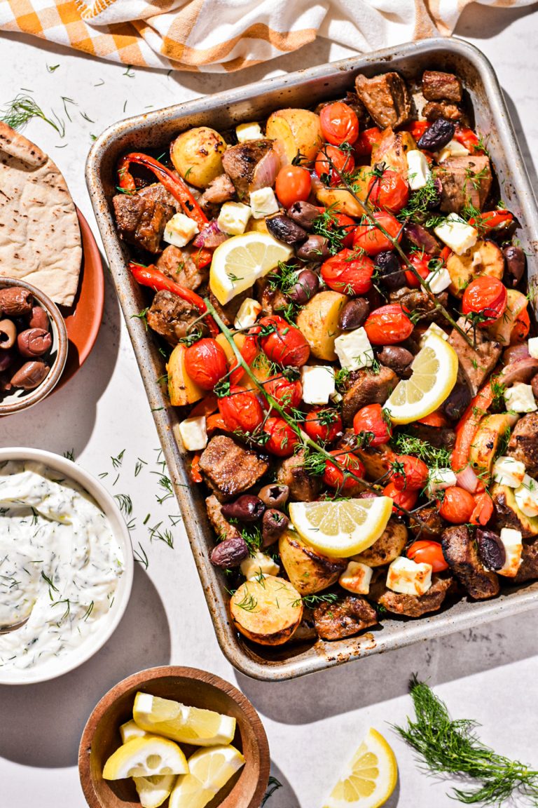 Overhead shot of sheet pan pork soulvaki on a sheet pan garnished with lemon wedges.