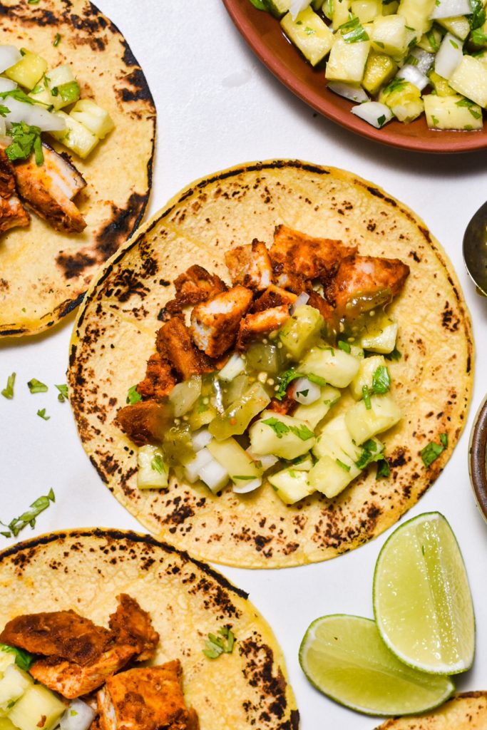 Close up of a chicken al pastor taco with pineapple pico de gallo and salsa verde.