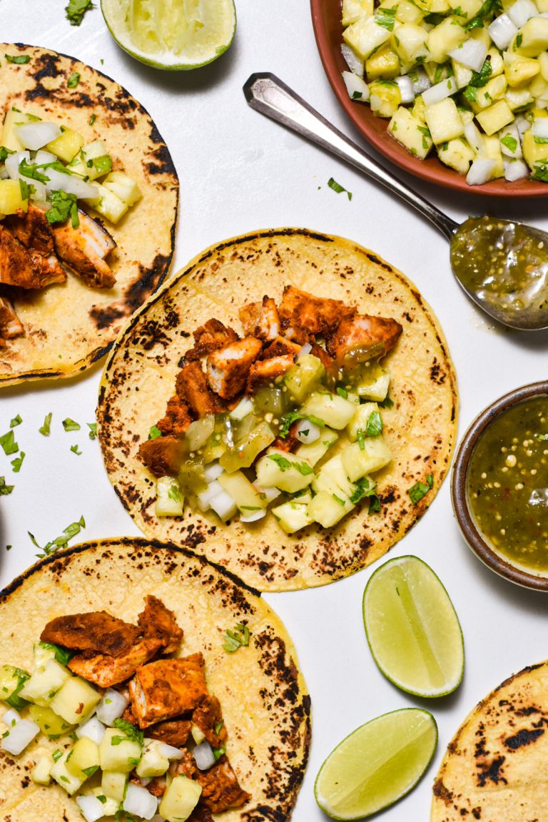Three corn tortillas with chicken al pastor, salsa verde, and pineapple pico de gallo.