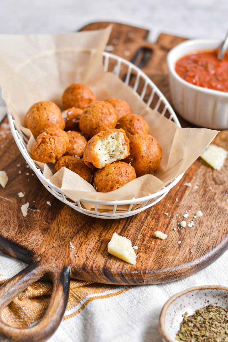 Polpette di parmigiano in a parchment lined basket on a wooden board.