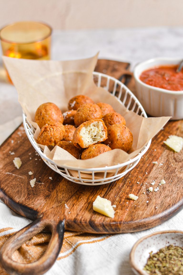 Close up of the polpette di parmigiano in a basket with one bitten in half.