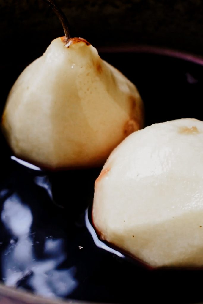 Peeled pears in the red wine mixture before simmering.
