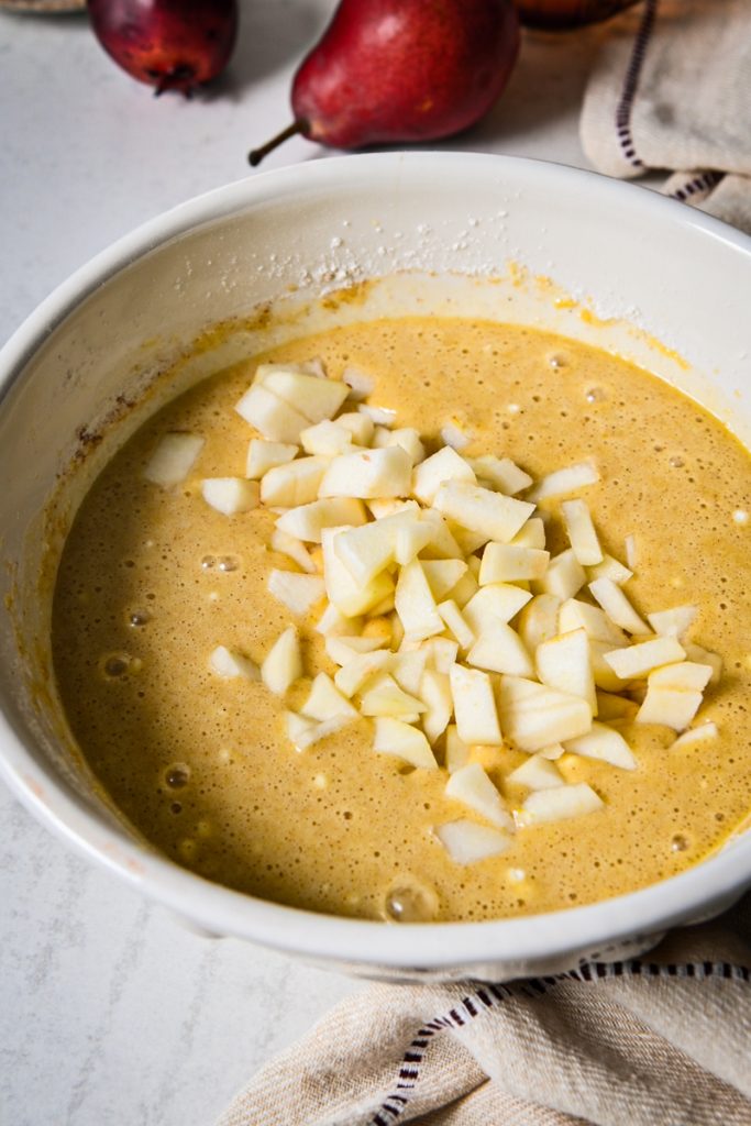 Chopped pears added to the cake batter in a bowl.