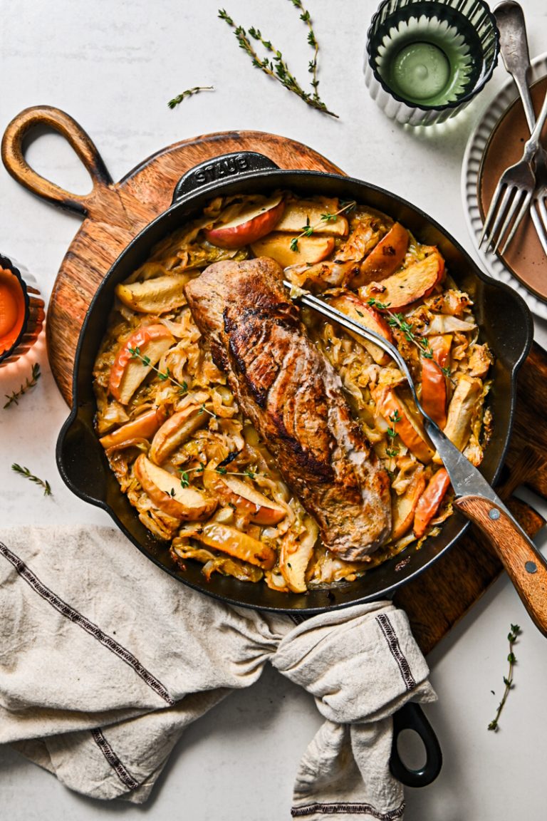 Overhead shot of pork loin baked in cabbage and apples in a skillet.