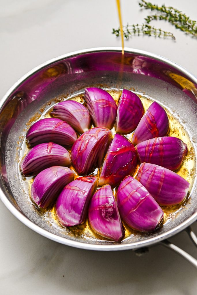 Drizzling honey over the red onion wedges in a skillet.