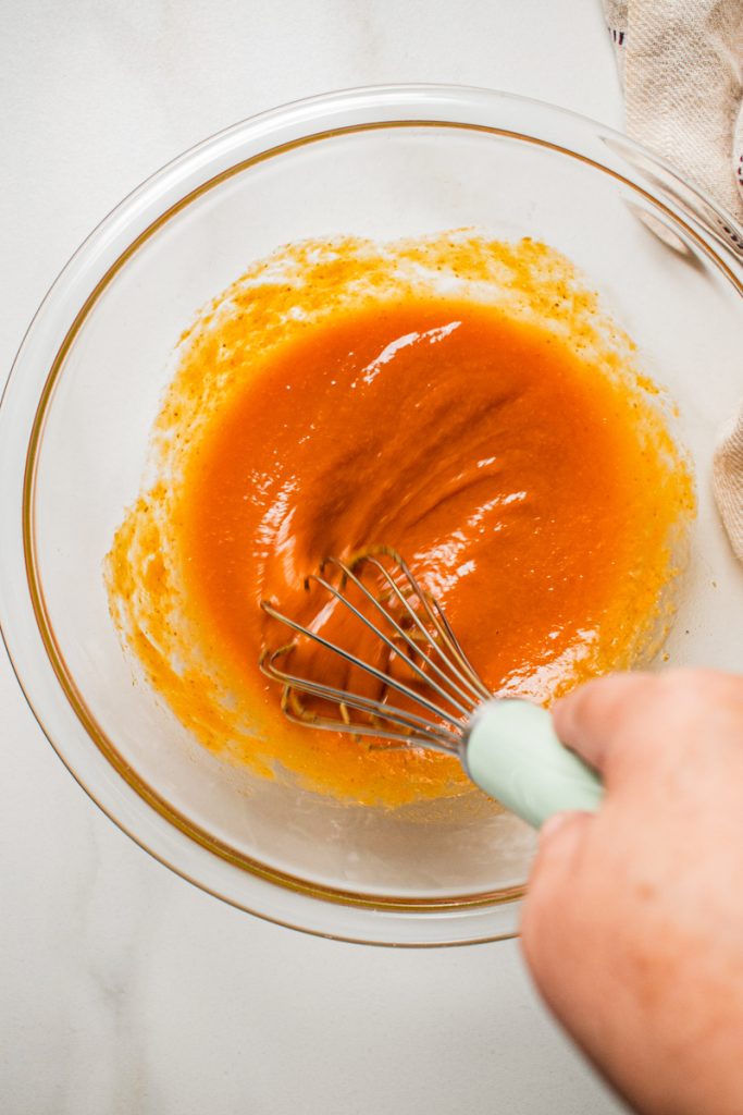 Whisking together the egg and pumpkin mixture in a mixing bowl.
