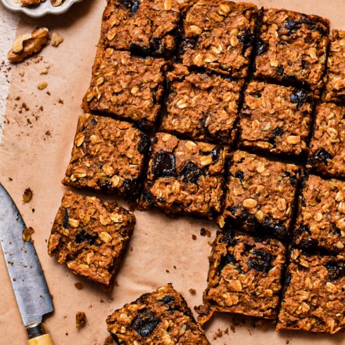 Close up of pumpkin chocolate baked oats sliced into squares on a parchment paper.