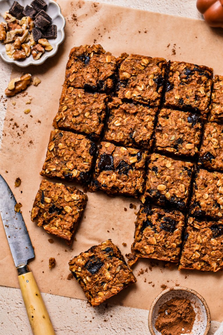 Close up of pumpkin chocolate baked oats sliced into squares on a parchment paper.