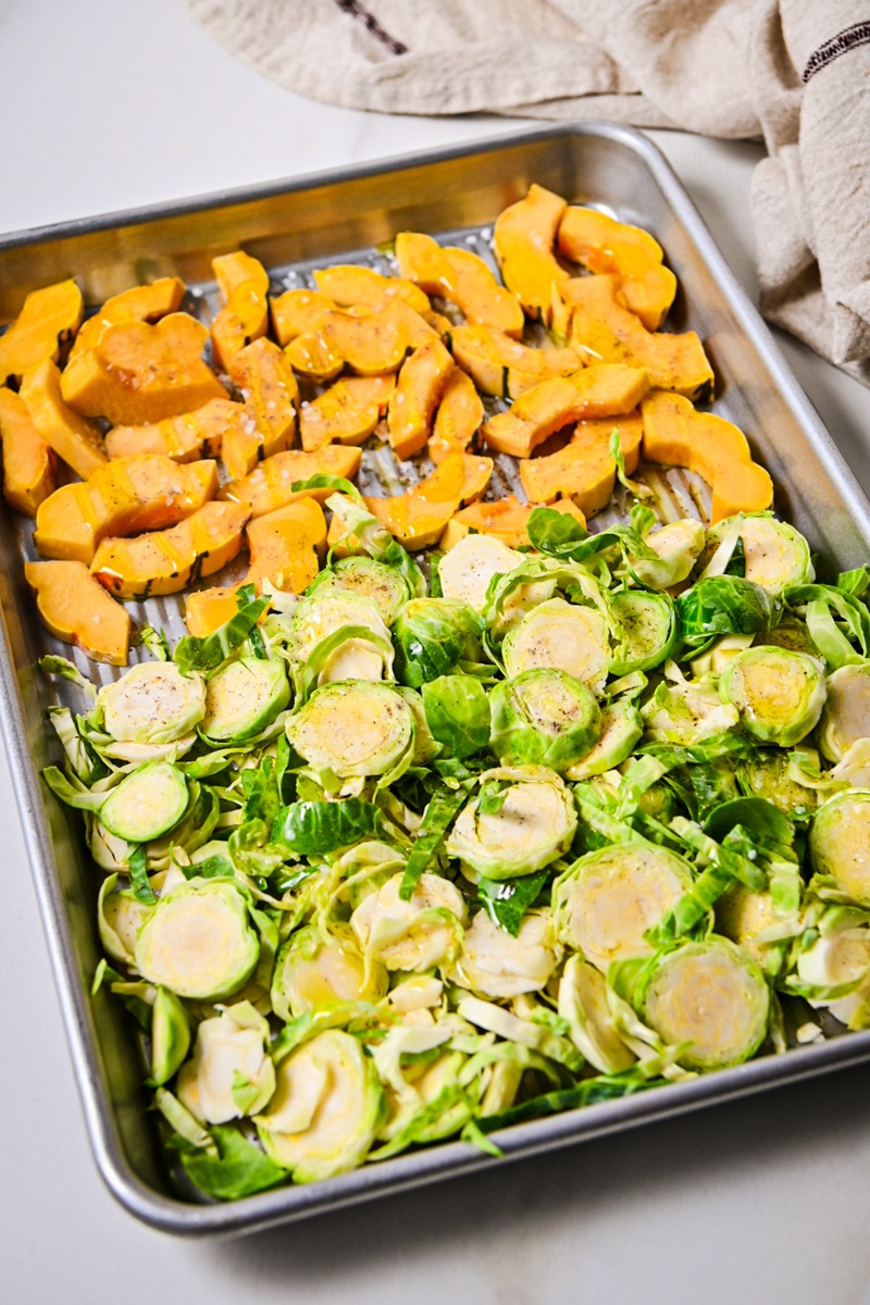 Brussels sprouts and delicata squash on a sheet pan to roast.