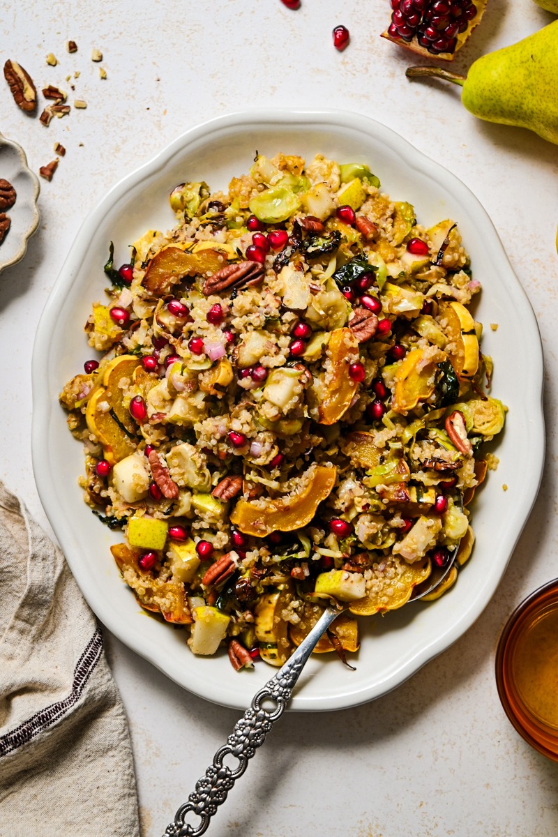 Quinoa fall salad on a white serving platter with a serving spoon.