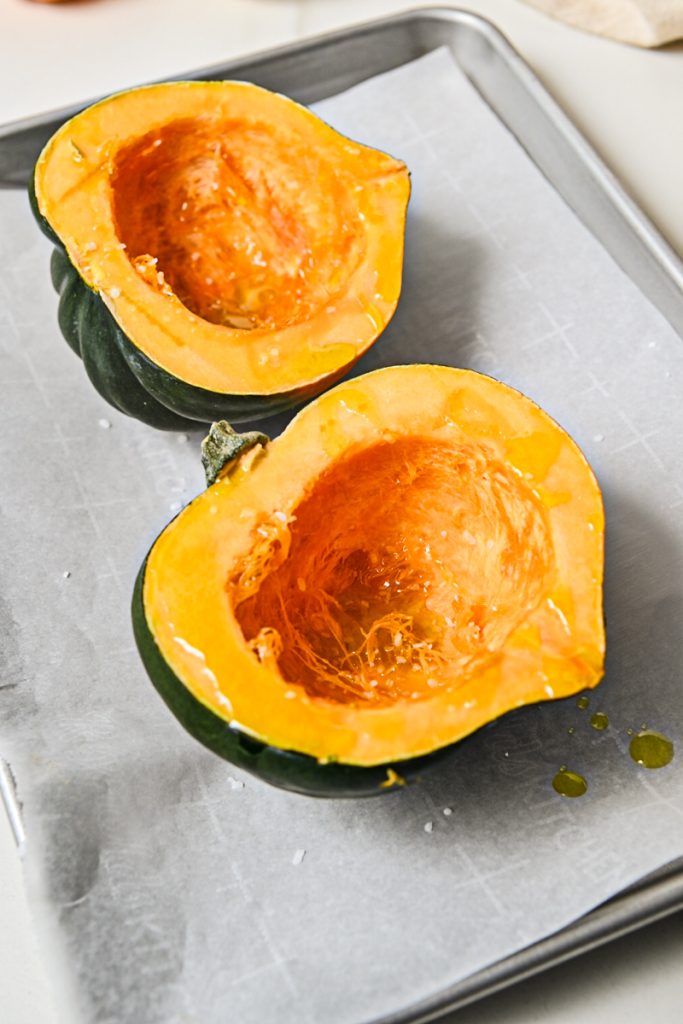 Acorn squash cut in half and placed on a sheet pan.