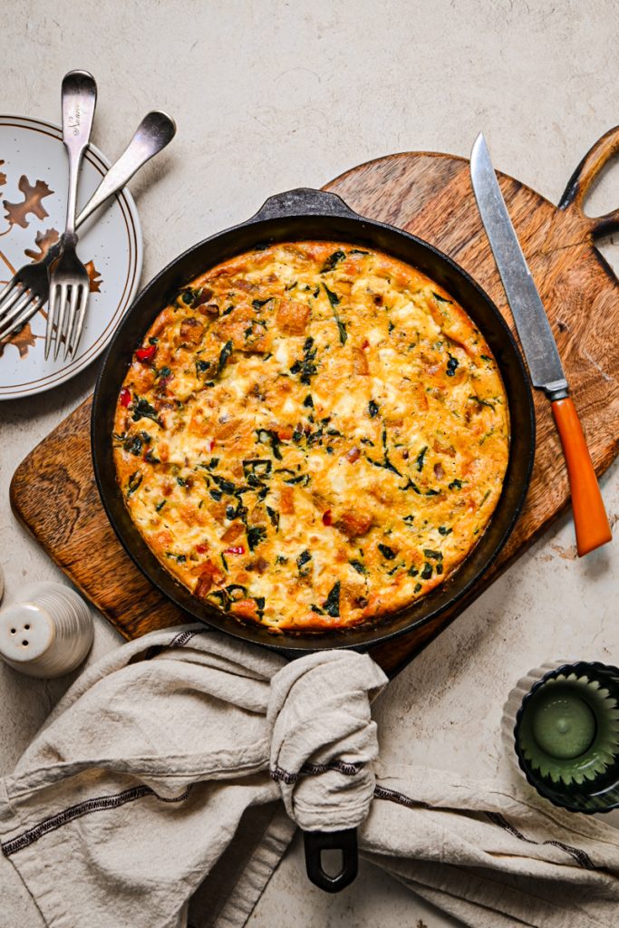 Butternut squash skillet quiche in a cast iron skillet on a wooden board.