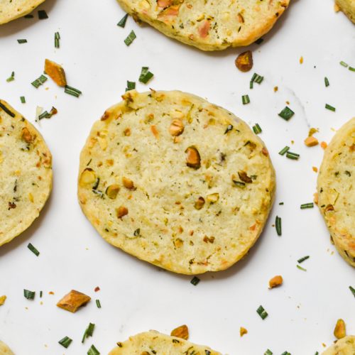 Close up of parmesan rosemary shortbread cookies lined up on a counter.