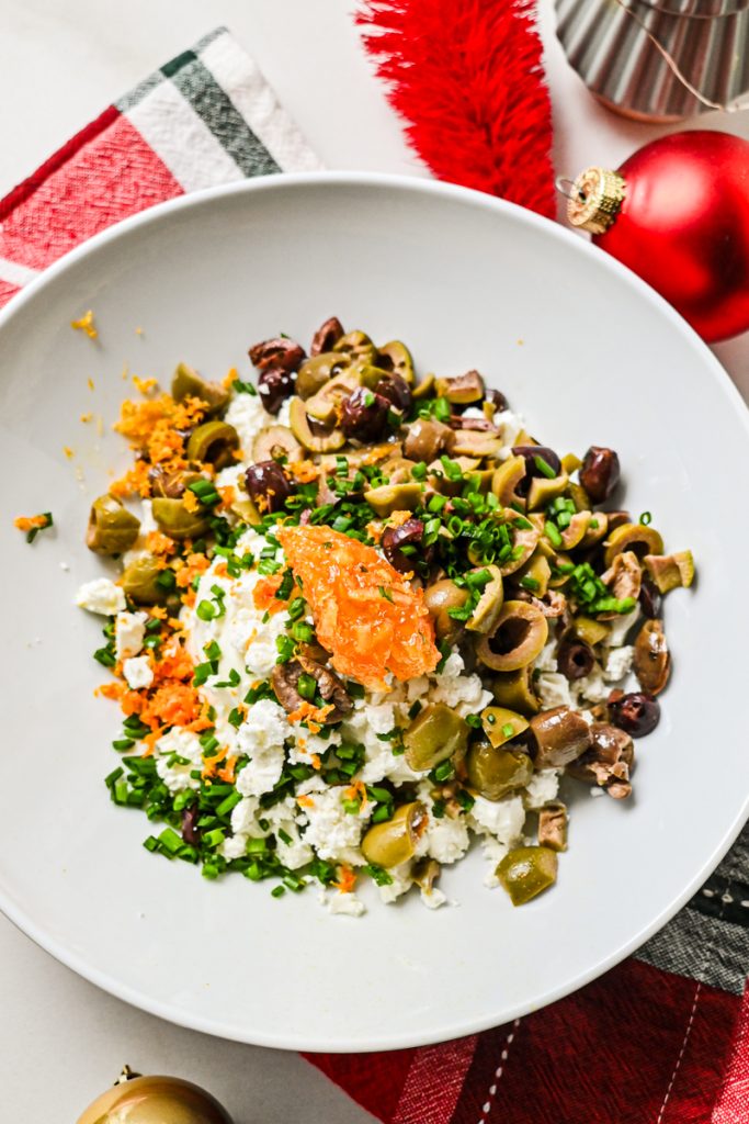 Cream cheese, feta cheese, olives, herbs and orange zest in a bowl before being mixed.