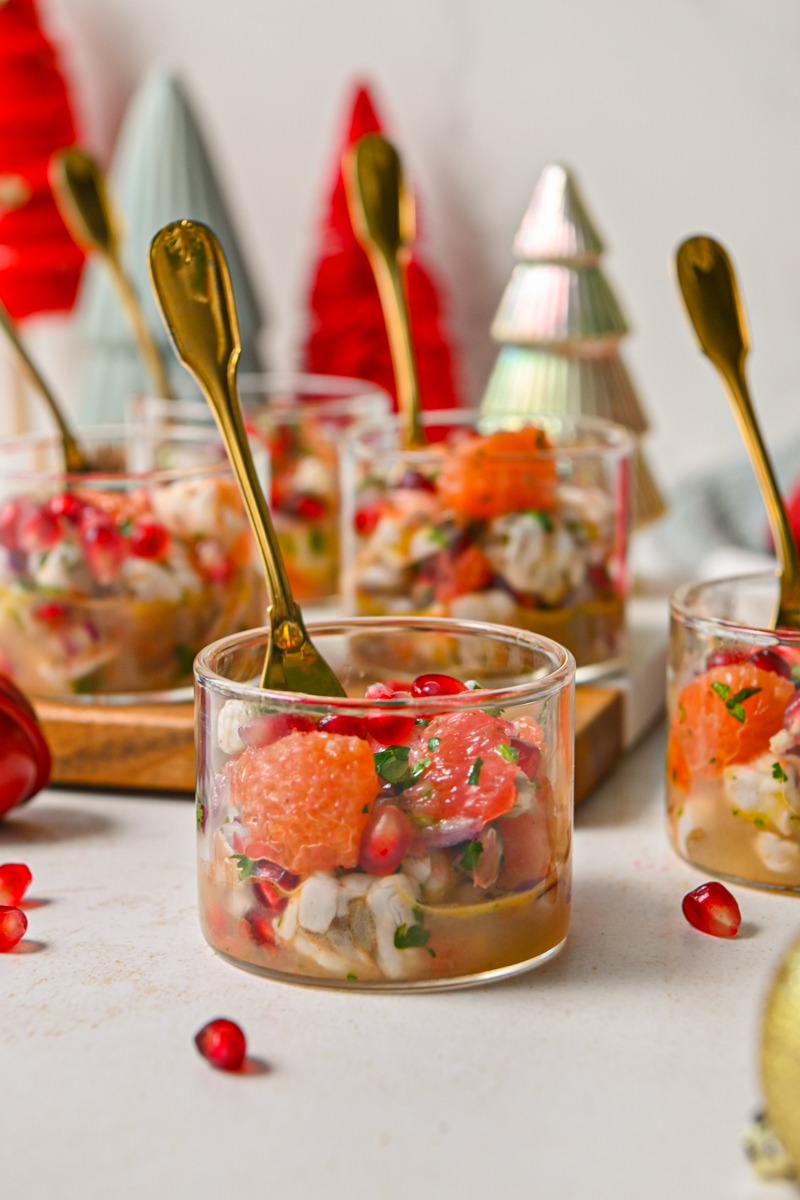 Side view of a glass of winter citrus shrimp ceviche with more glasses around it.