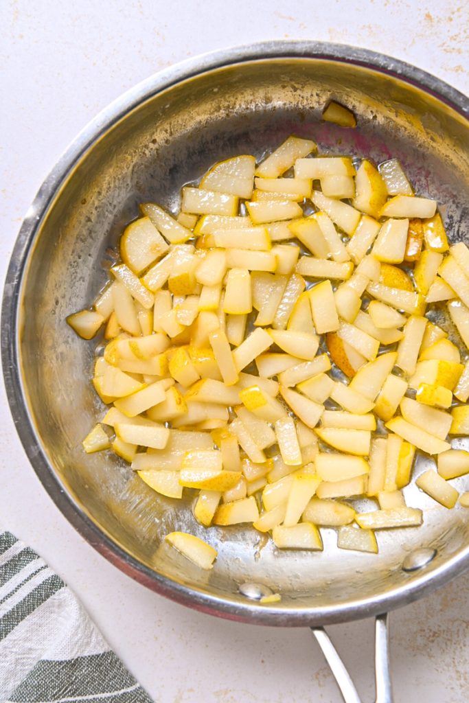 Overhead shot of pears sautéing in a skillet.