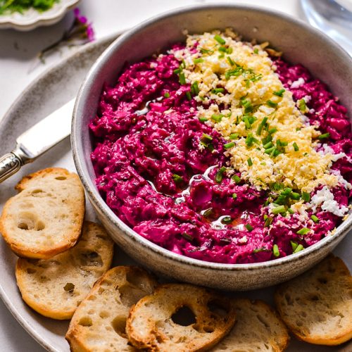 Beetroot and tuna dip in a bowl served with crostini on the side.