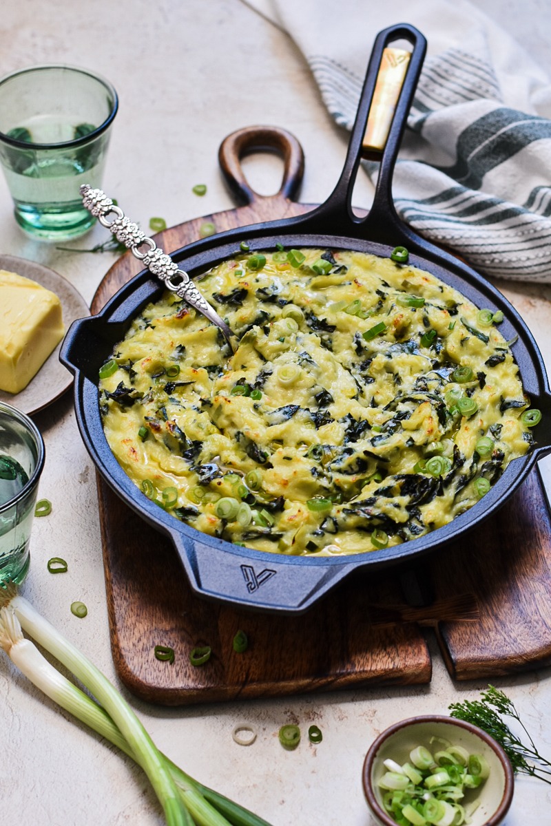 Side view of Irish colcannon in a skillet on a wooden board.