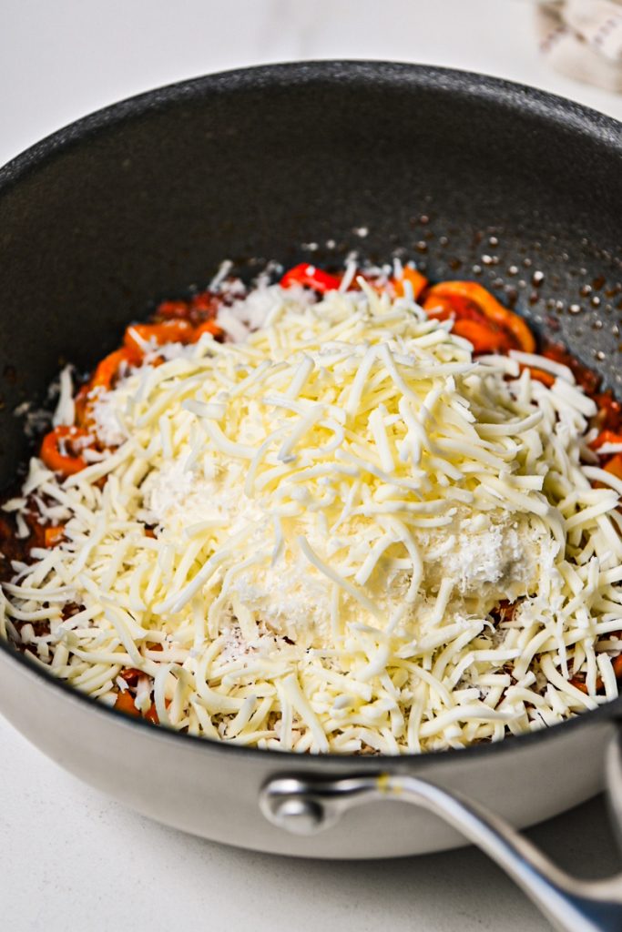 Ricotta and mozzarella cheeses added to the sweet pepper mix in a skillet.