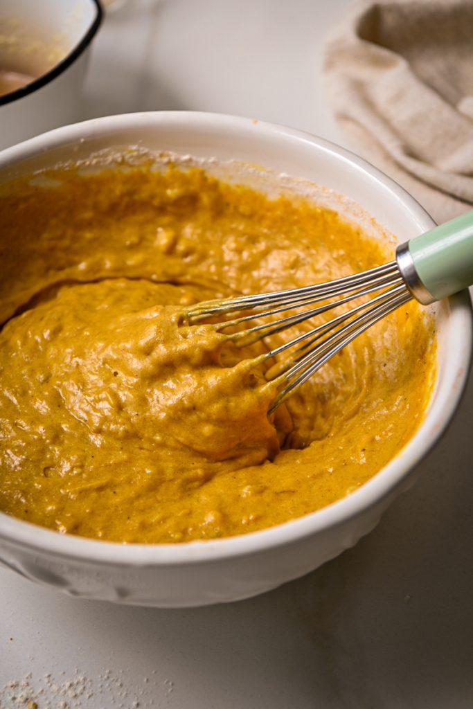 Dry ingredients whisked into the wet ingredients in a mixing bowl.