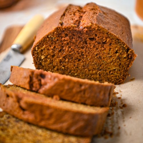 Close up of golden milk banana bread on a wooden board with some slices off the end.