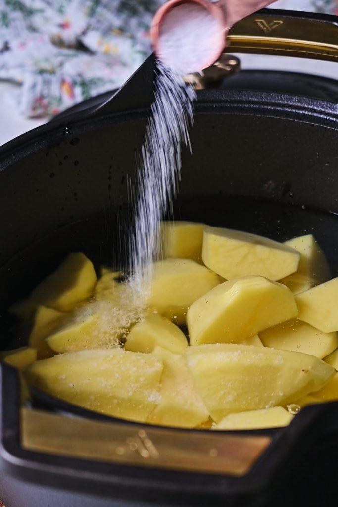 Potatoes and salt added into a large Dutch oven pot.