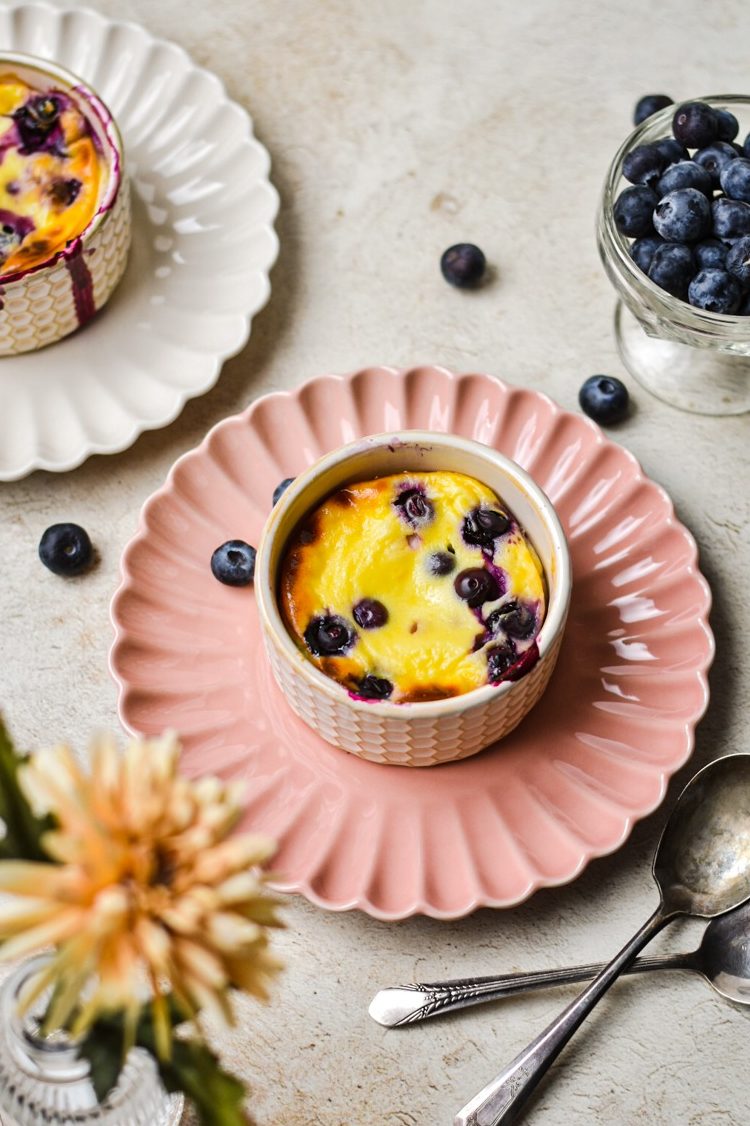 Berry baked yogurt in a ramekin served on a pink plate.