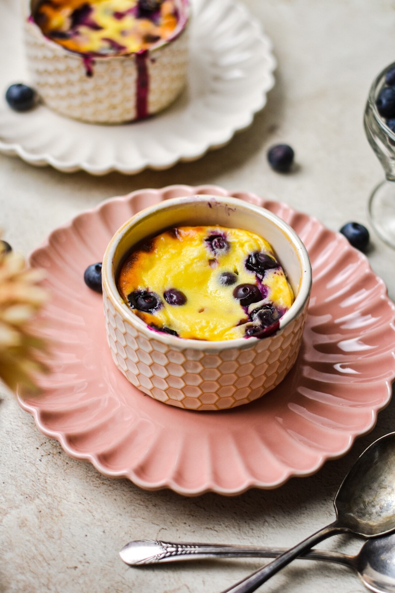 Berry baked yogurt in a ramekin which is on a pink plate.