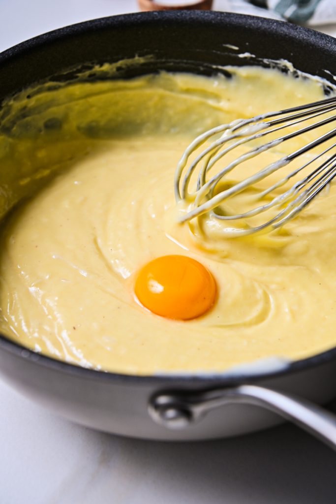 Egg yolk added to the bechamel sauce in a skillet.