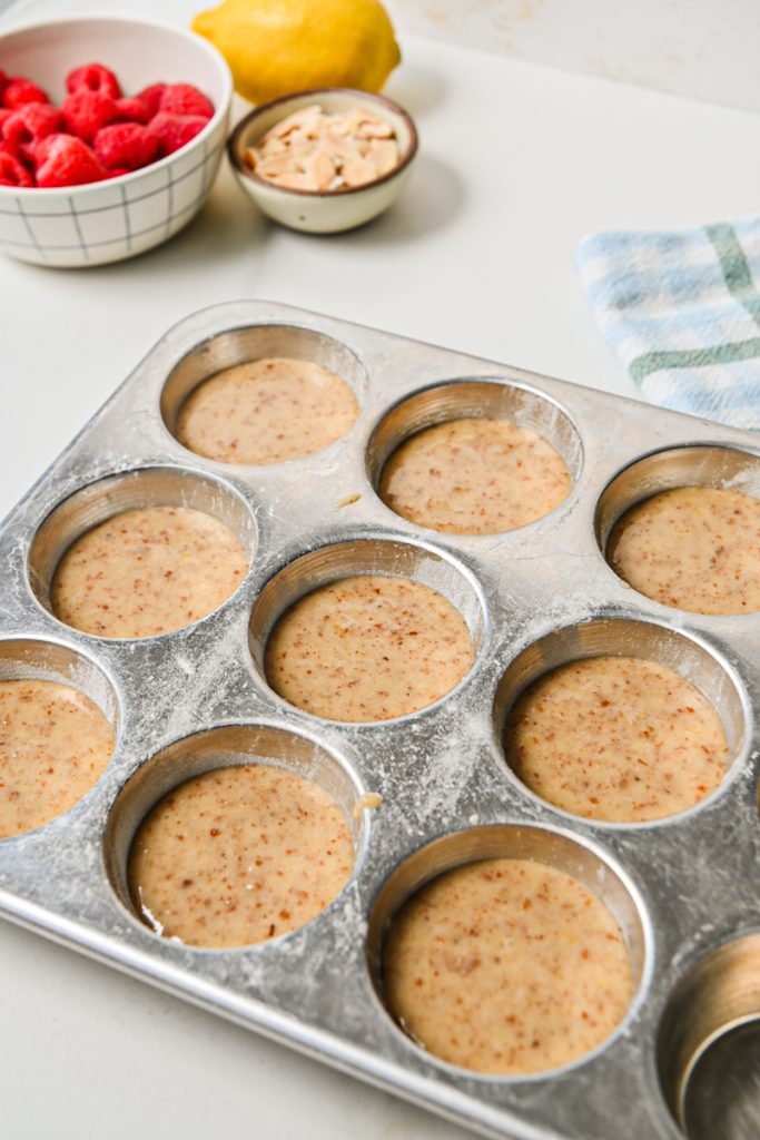 Financier muffin batter divided into a muffin tin.