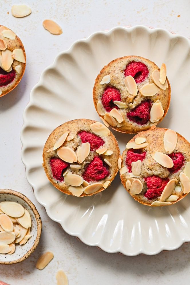 Overhead shot of baked raspberry financier muffins on a plate.