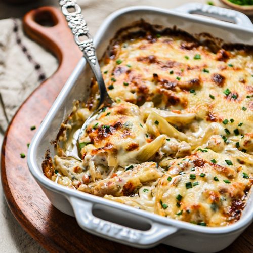 Serving spoon in a white baking dish of fennel gratin.