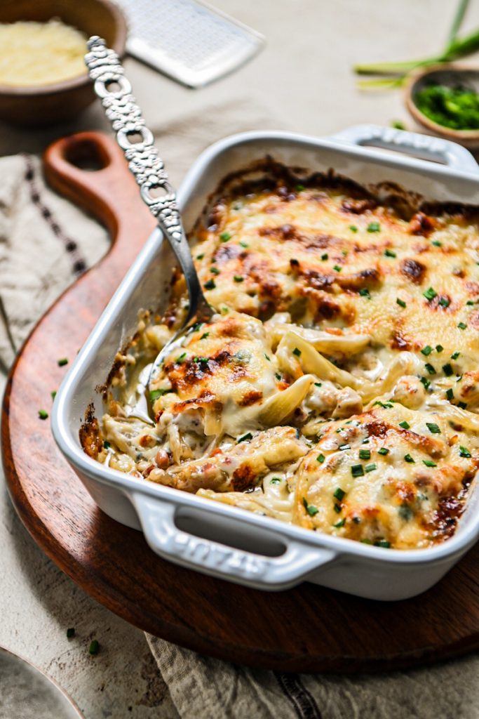 Serving spoon in a white baking dish of fennel gratin.