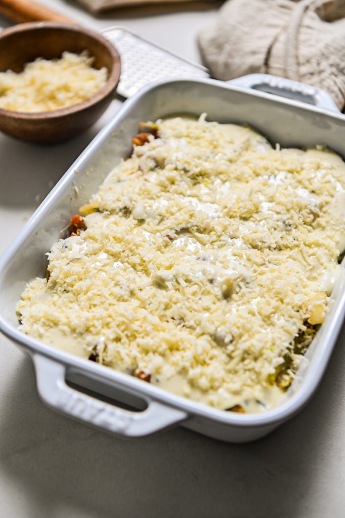 Gorgonzola cream and parmesan cheese placed on top of the fennel mixture in a baking dish.