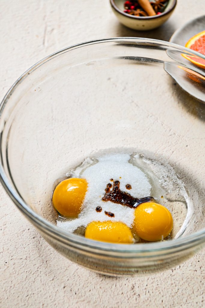 Egg yolks, sugar and vanilla in a glass bowl.