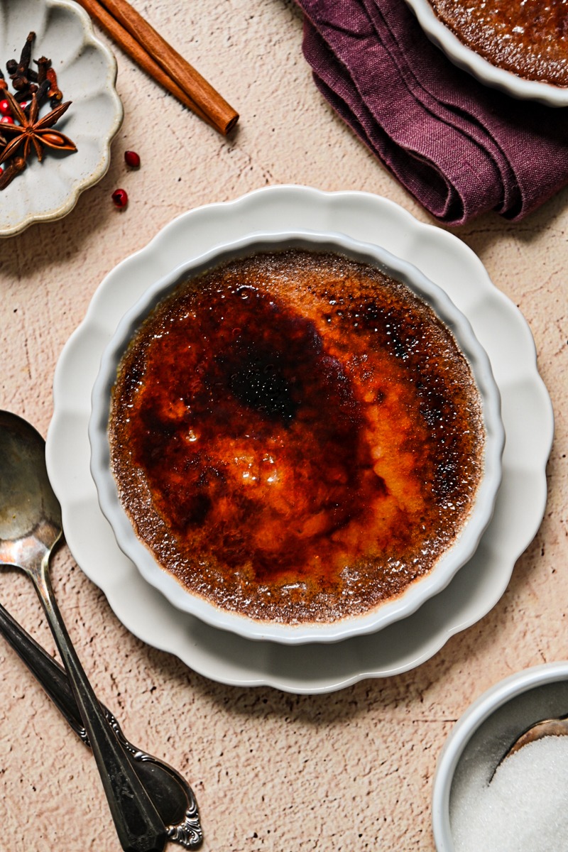 Overhead shot of mulled wine creme brulee in a ramekin on a fluted plate.