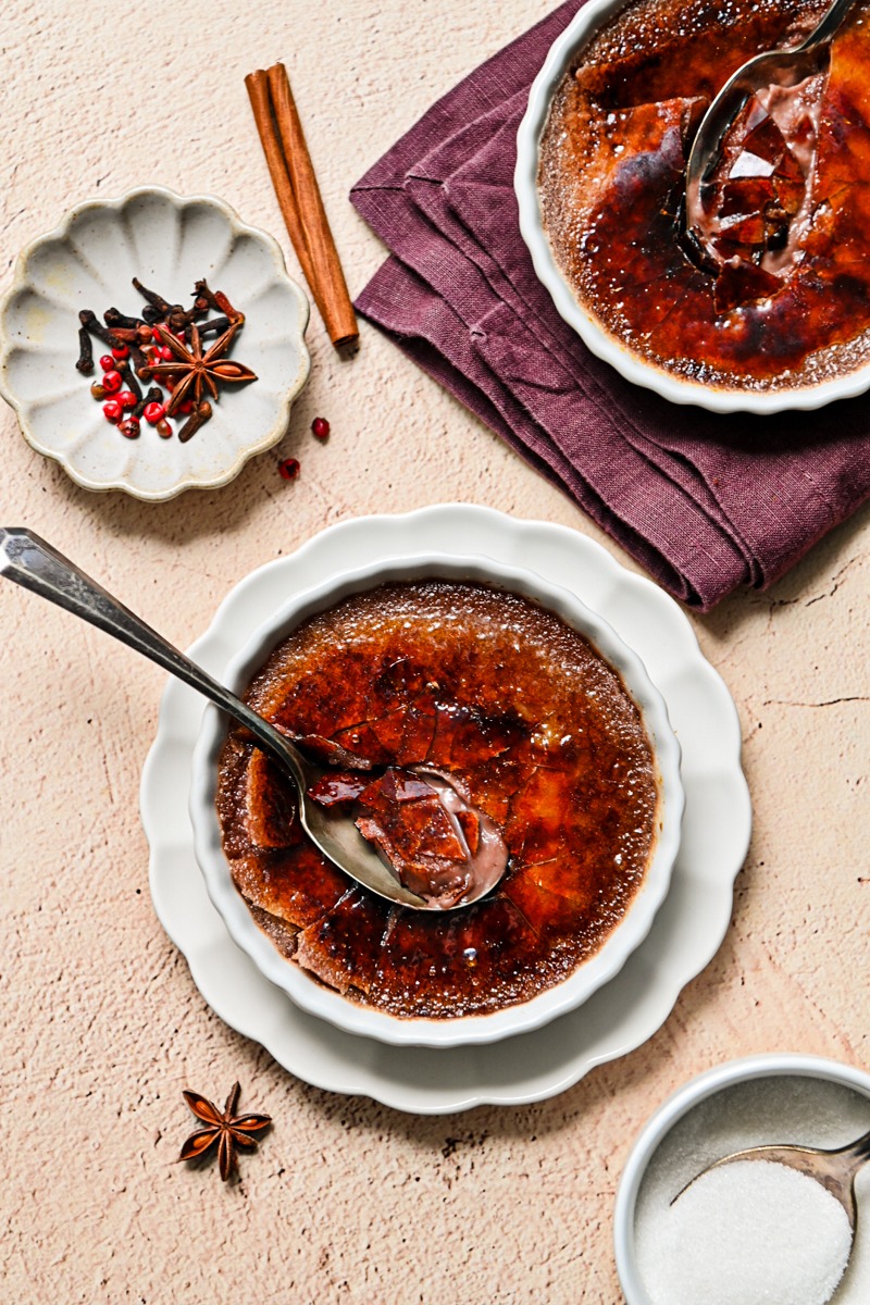 Overhead shot of two mulled wine creme brulees, both cracked with spoons.
