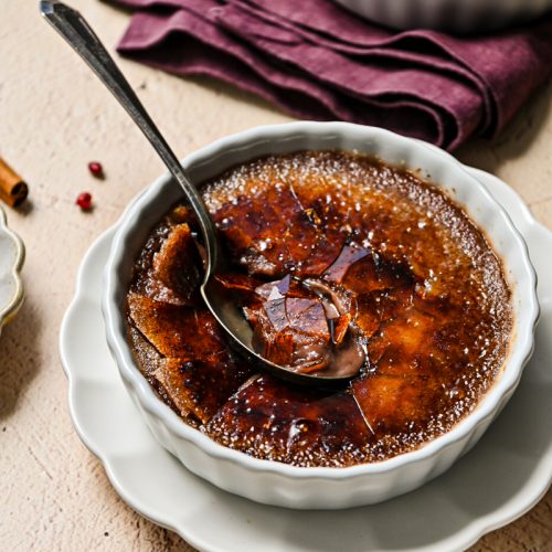 Side view of a mulled wine creme brulee with a spoon inside.