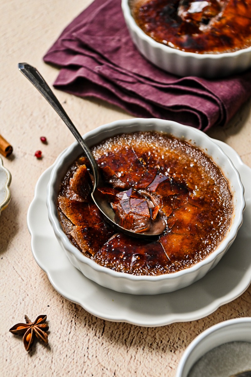 Side view of a mulled wine creme brulee with a spoon inside.