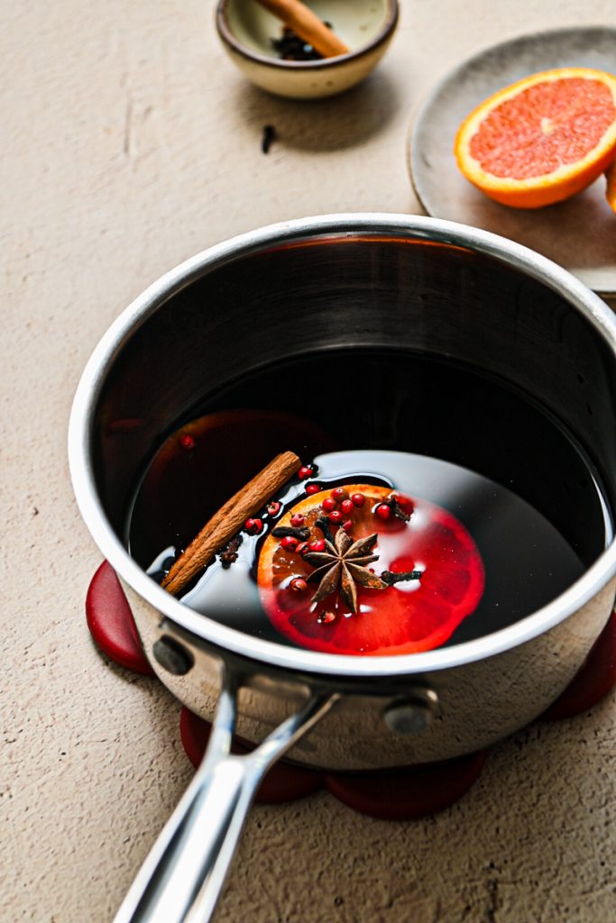 Wine with aromatics and an orange slice in a saucepan.